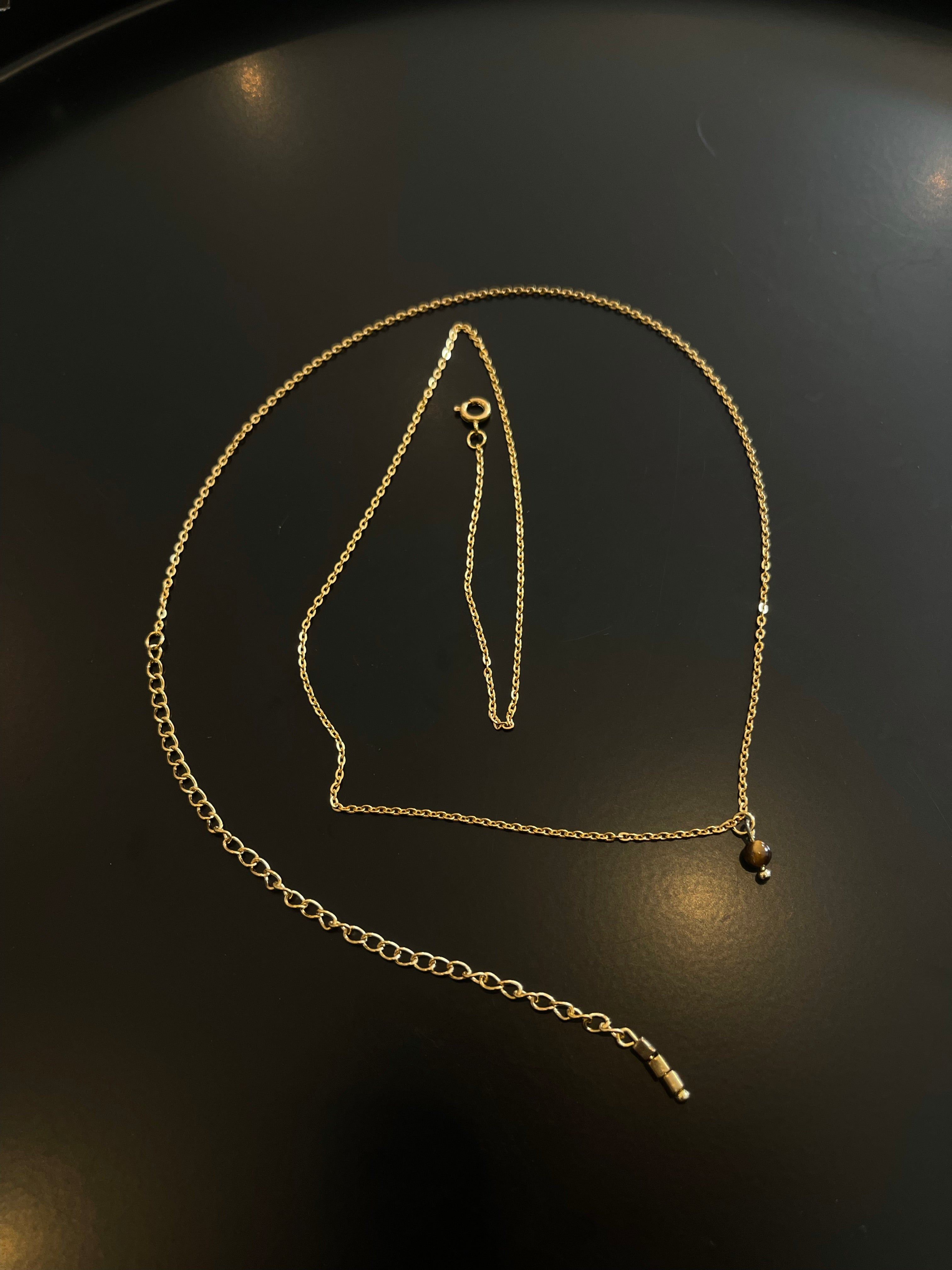 Golden minimalistic body chain with three square tiger eye gemstones at the end and one round tiger eye pendant.